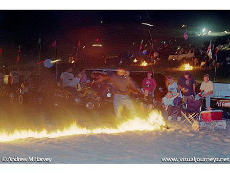 Boy in Fire:  Gasoline poured into the sand and then ignited serves as daring entertainment to drive through.  This man chooses to simply roll through  the fire.  Gasoline poured in the sand destroys habitat for many dunes creatures.